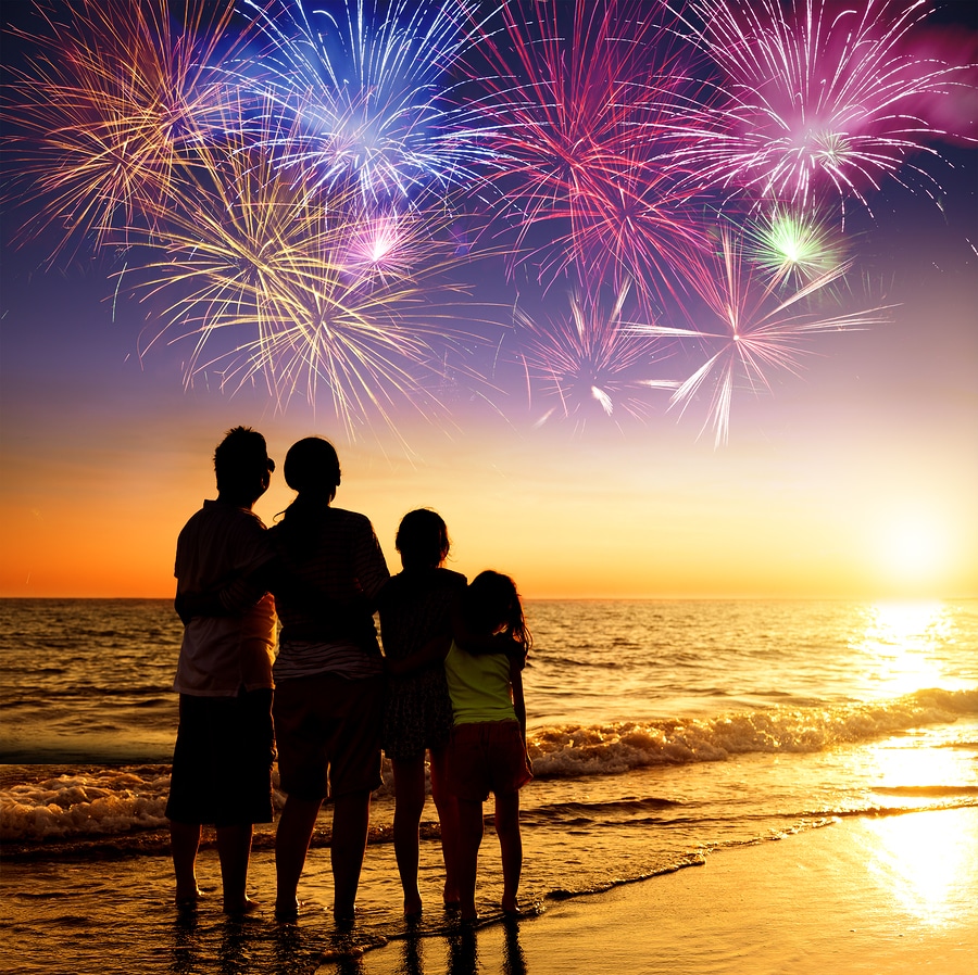 happy family watching the sunset and independence day firework on the beach