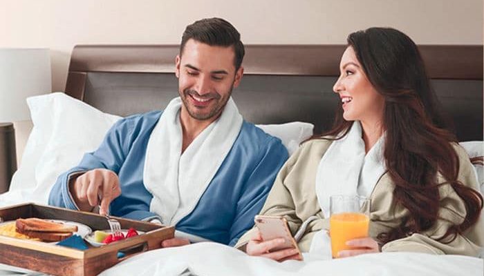 Dad and mom relax in bed in Sobel at home luxury hotel robes