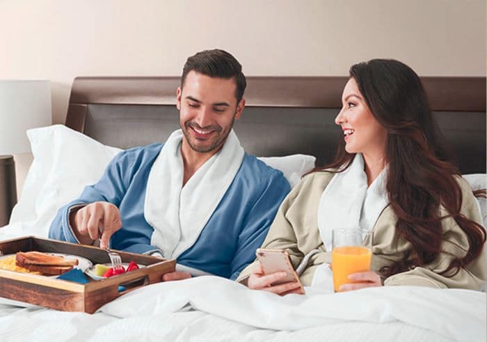 Dad and mom relax in bed in Sobel at home luxury hotel robes