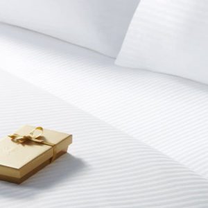 Ni nights hotel bedsheets by Sobel Westex in luxury hotel room with gift box on the bed