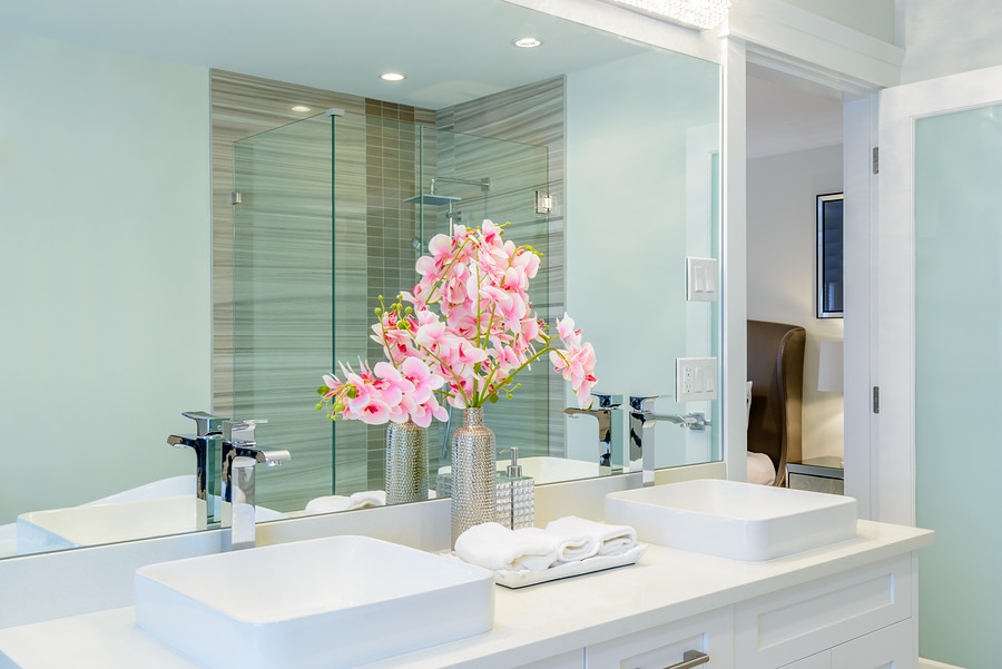 luxury hotel bathroom with orchids and white folded hand towels next to the sink