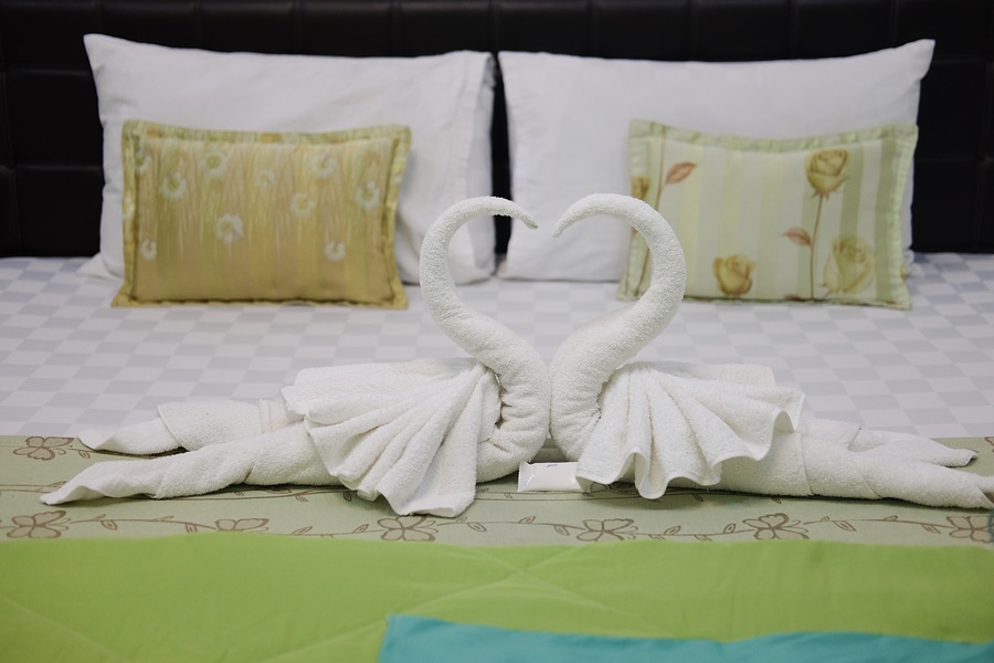 Pillow and blown pillow and fold the towel as a swan kiss each other on the white bed 