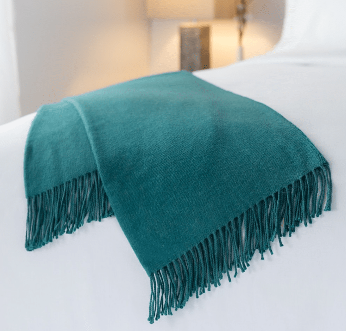 teal color, folded Alpaca throw by Sobel at Home on hotel bed
