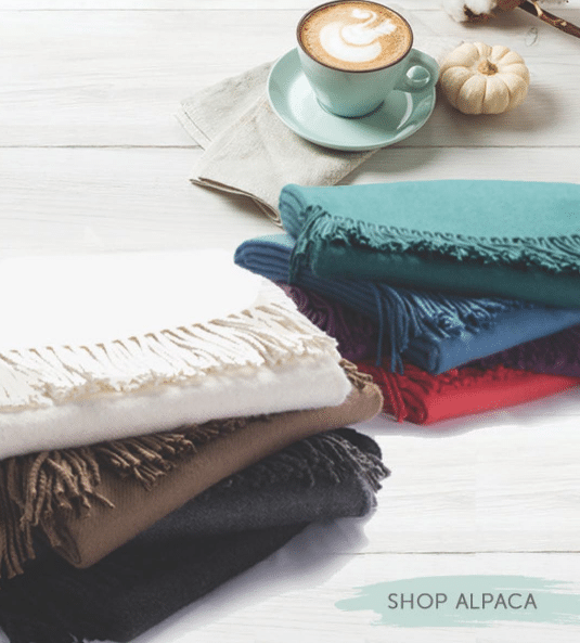 Sobel Westex luxury alpaca blankets in several colors with a cup of coffee in fall setting