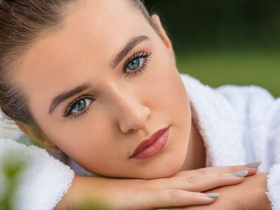 Beautiful young woman relaxing in robe outside at health spa