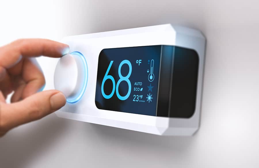 Hand turning a home thermostat knob to set temperature cooler to get a better night's sleep