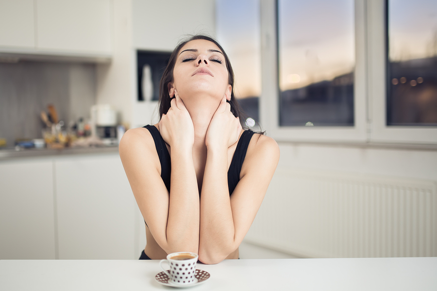 achy woman after trouble sleeping at table drinking coffee