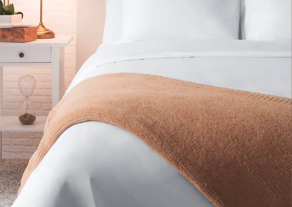 Sobel Westex Sahara Nights white bed sheets on a beautiful hotel bed with a soft brown alpaca throw