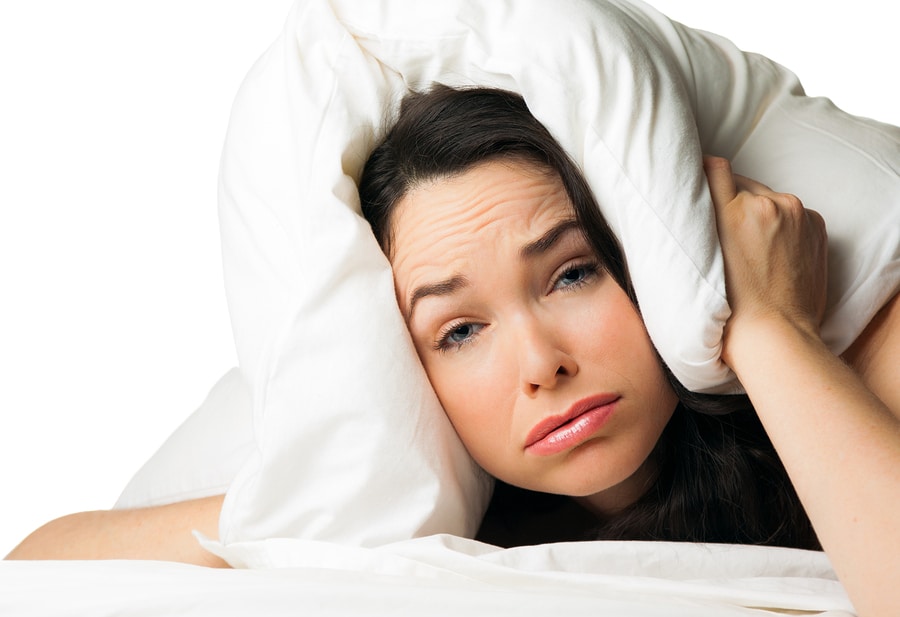 woman with hotel pillow over her head can't sleep due to noise