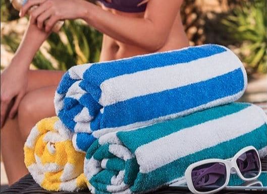 Sobel Westex striped pool towels rolled next to woman swimmer