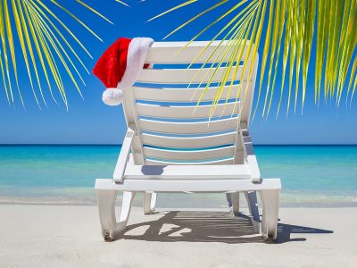 Christmas in July with santa hat on a chaise lounge on a tropical beach
