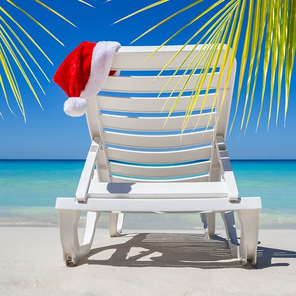 Christmas in July with santa hat on a chaise lounge on a tropical beach
