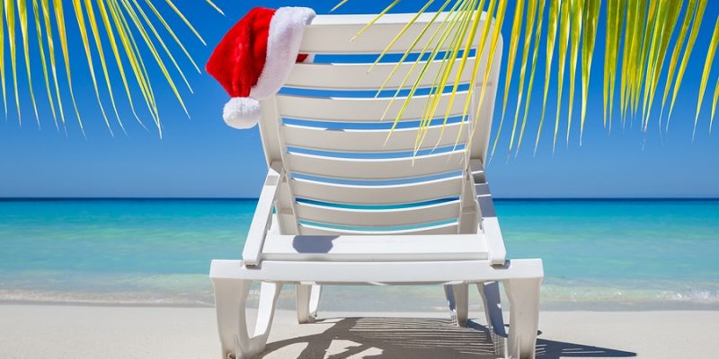 Christmas in July with santa hat on a chaise lounge on a tropical beach