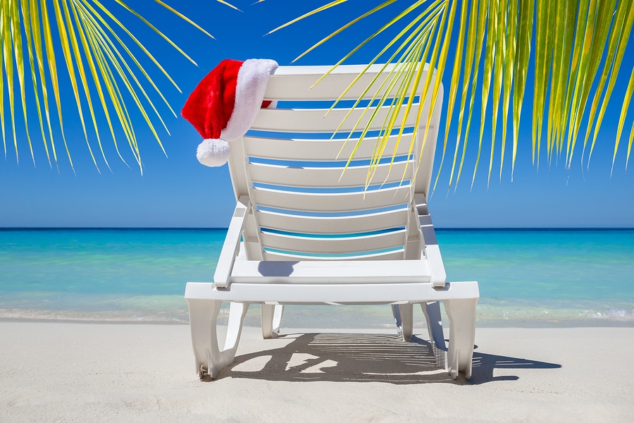Christmas in July with santa hat on a chaise lounge on a tropical beach