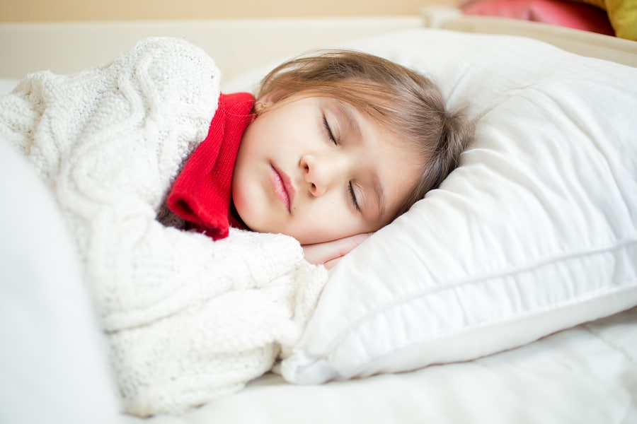 Sleeping girl in Christmas scarf on a soft luxury pillow