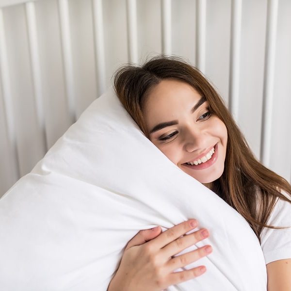 Young woman hugging a fluffy white pillow in a pillow protector