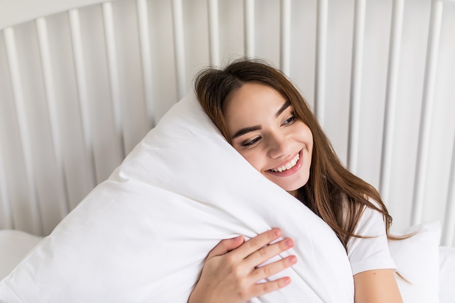 Young woman hugging a fluffy white pillow in a pillow protector