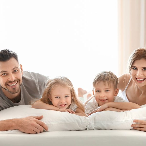 Happy family on bed with pillows denoting healthy lifestyle pillow fillings