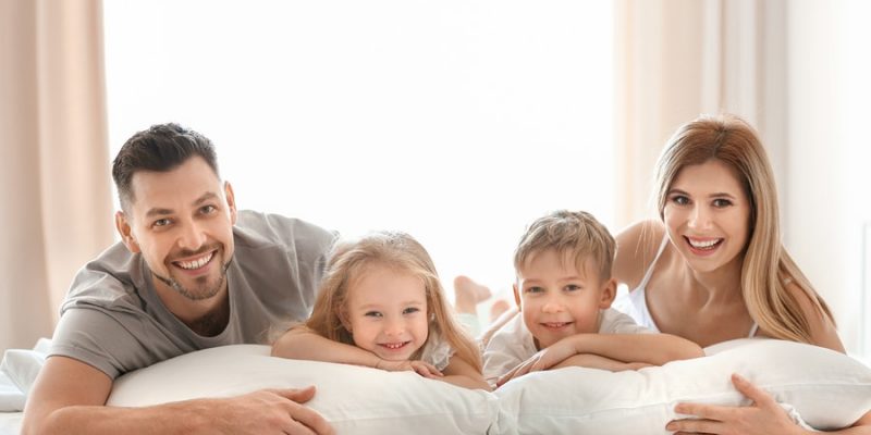 Happy family on bed with pillows denoting healthy lifestyle pillow fillings