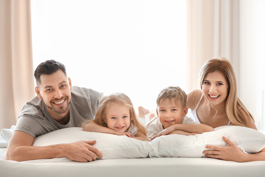 Happy family on bed with pillows denoting healthy lifestyle pillow fillings