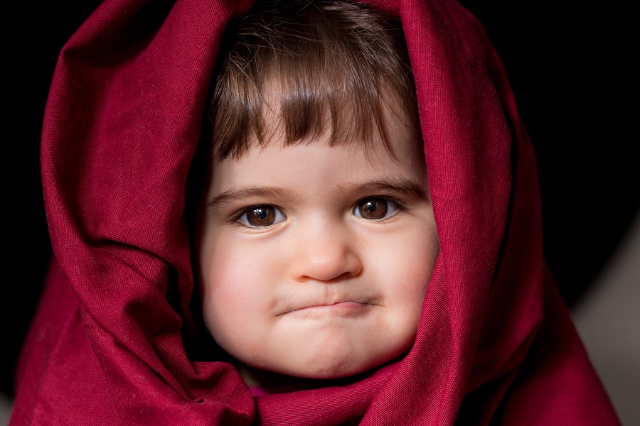 Toddler girl dressed in red bed sheet to look like Little Red Riding Hood
