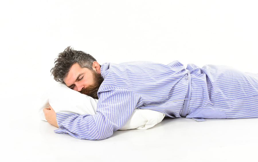 Man with sleepy face lies on pillow.