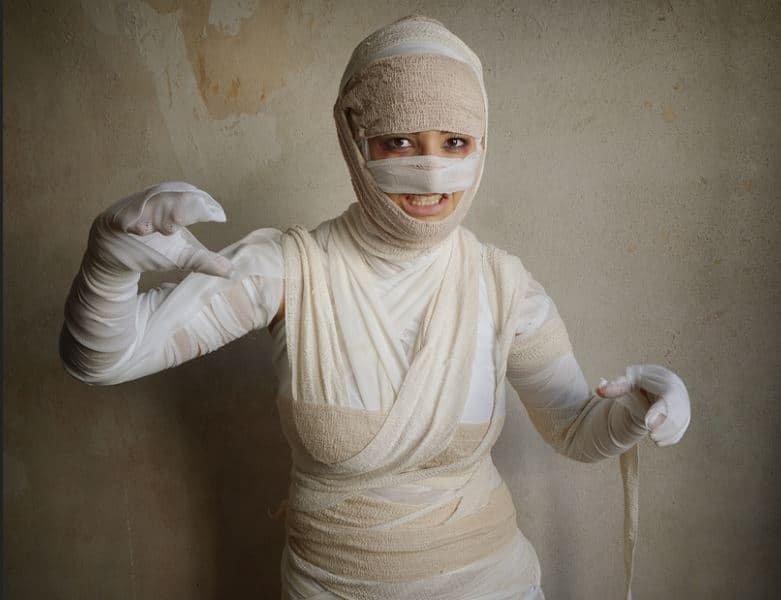 Girl dressed as a mummy with torn bandages or sheets wrapped around her for a Haloween costume