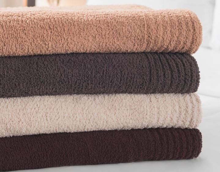 Four Sobel Westex chenille blankets stacked in different colors