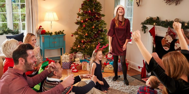 Multi Generation Family Playing Charades As They Celebrate Christmas At Home Together