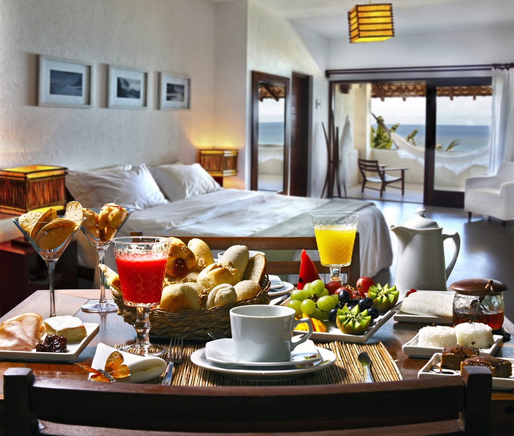 Gourmet breakfast laid out in luxury hotel room with ocean views