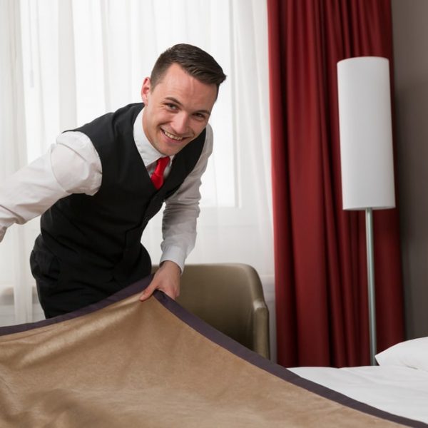 Butler straightening the bedding in a luxury hotel room