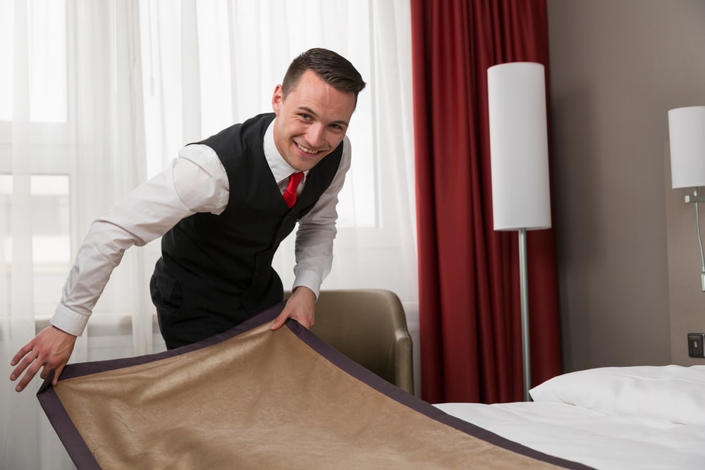 Butler straightening the bedding in a luxury hotel room