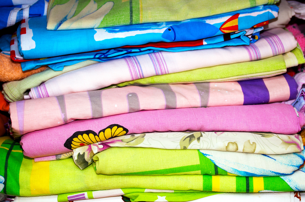 colorful stack of old bedsheets many colors and patterns