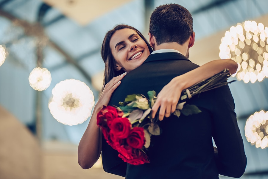 Beautiful loving couple is spending time together in modern restaurant. Attractive young woman in dress and handsome man in suit are having romantic dinner. Celebrating Saint Valentine's Day.