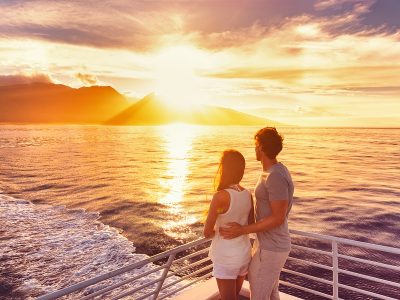 Couple watch sunset from deck of a luxury cruise ship