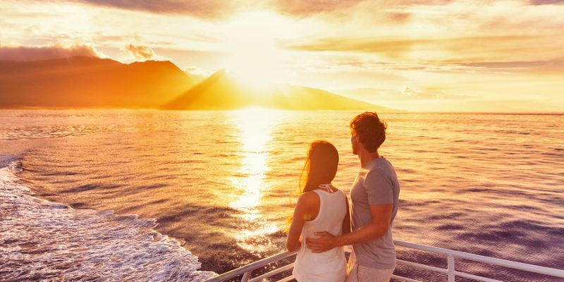 Couple watch sunset from deck of a luxury cruise ship