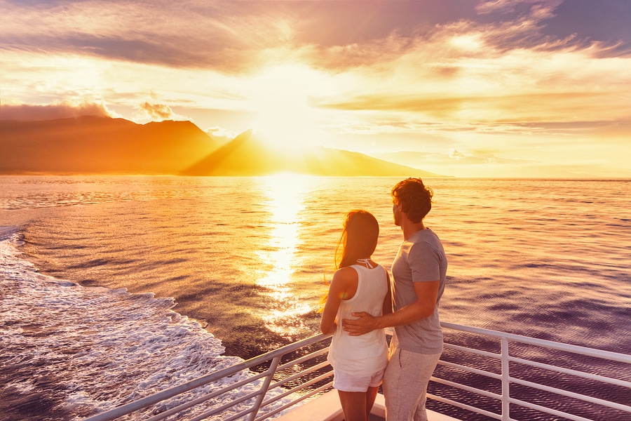 Couple watch sunset from deck of a luxury cruise ship
