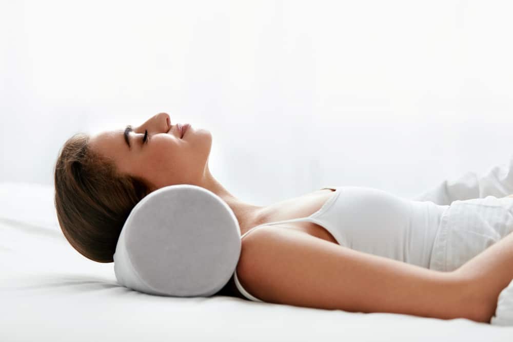 woman relaxing peacefully on a white neckroll pillow