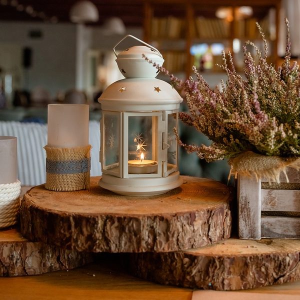 fall season home decoration made of cozy candles and dried floral arrangement on wood blocks with home in background