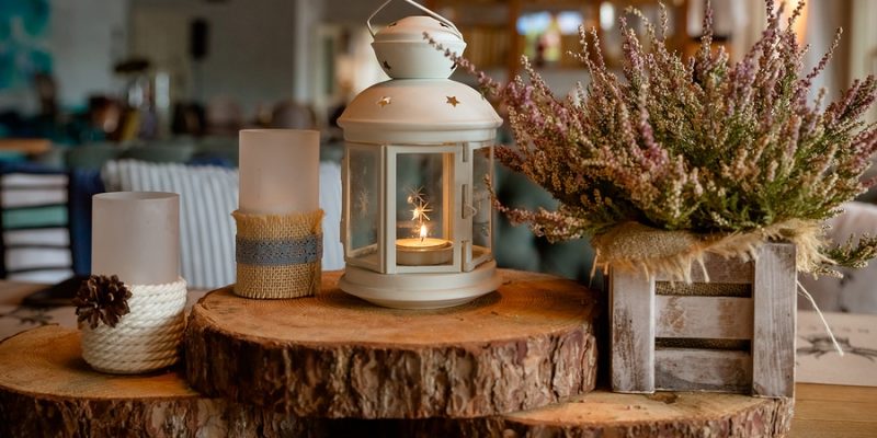 fall season home decoration made of cozy candles and dried floral arrangement on wood blocks with home in background