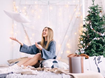 Happy girl in bathrobe tossing her new bellaure duo feather pillow in front of a christmas tree