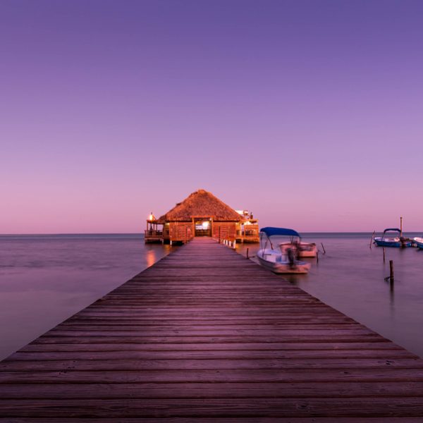 dream vacation bungalo lit up at sunset over water near great blue hole, belize