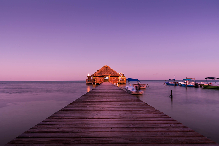 dream vacation bungalo lit up at sunset over water near great blue hole, belize
