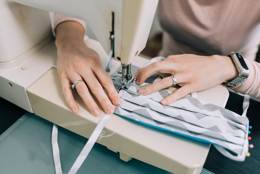 Woman's hands using the sewing machine to sew the face home made diy medical mask during the coronavirus pandemia.