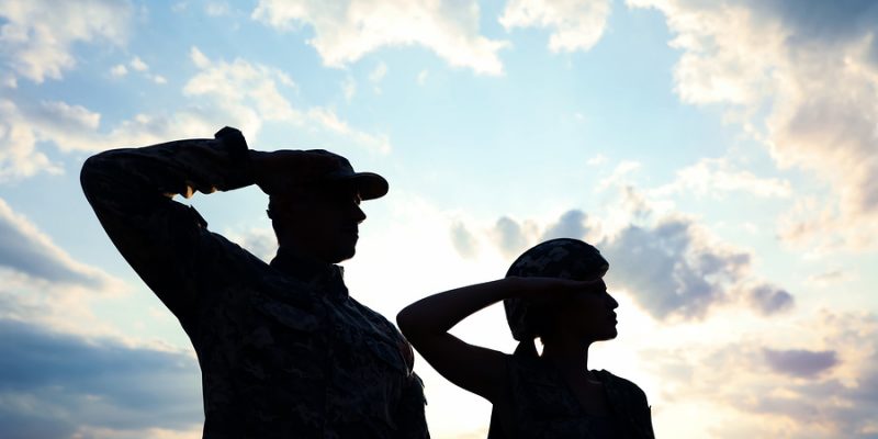 Soldiers in uniform saluting against the sky at armed forces celebration