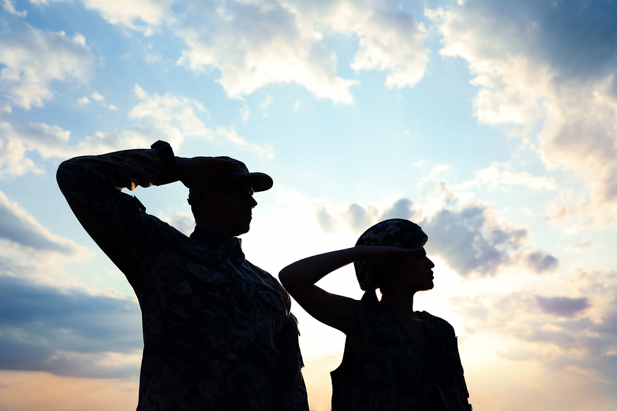 Soldiers in uniform saluting against the sky at armed forces celebration