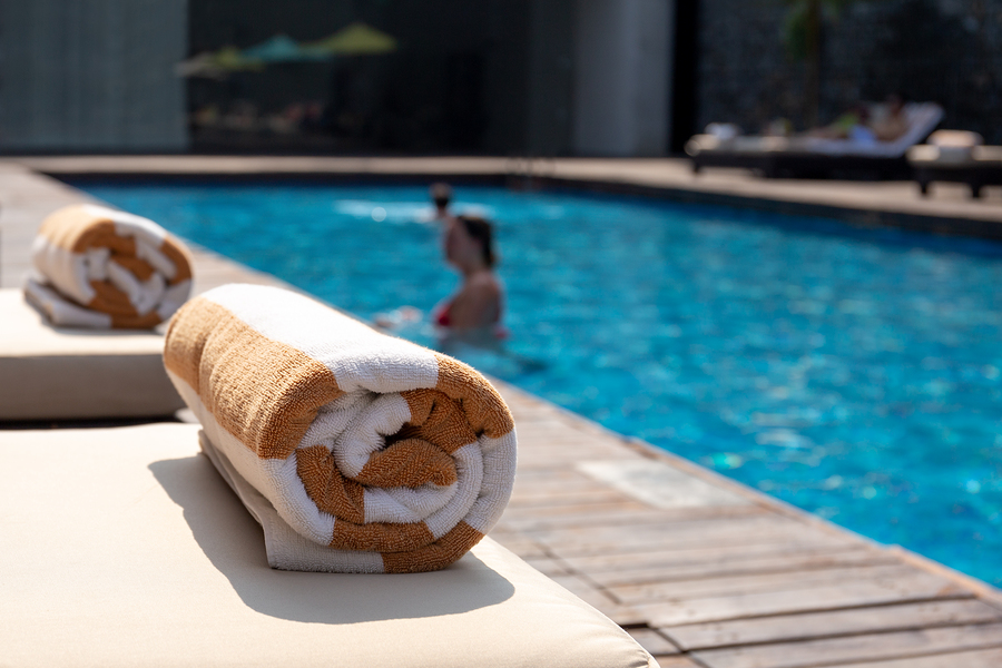 Sobel Westex Home Pool Towel Brown and White rolled poolside with woman in pool