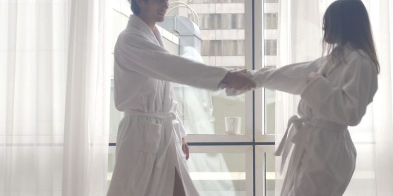 A couple dancing in a hotel room wearing luxury hotel spa bathrobes