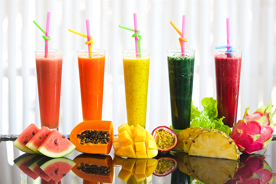 tropical fruit smoothie, on a table in glasses of watermelon neck with papaya pineapple mango and passion fruit and pithaya, salad greens drink, healthy drinks on a white background, mirror reflection of fruits and juices