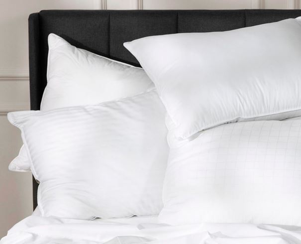 PIle of four Sobel Westex luxury hotel pillows on a hotel bed against the headboard